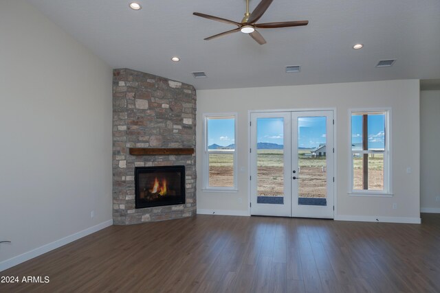 unfurnished living room featuring lofted ceiling, a stone fireplace, dark wood-type flooring, and french doors