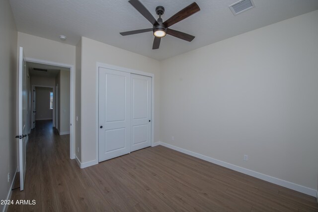 unfurnished bedroom featuring hardwood / wood-style flooring, ceiling fan, and a closet