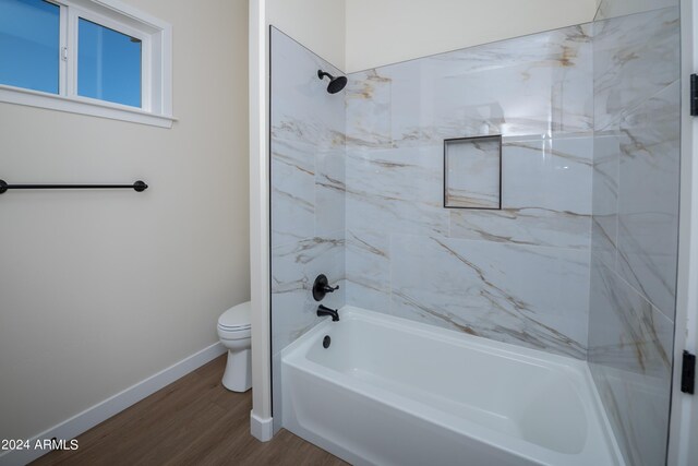 bathroom featuring tiled shower / bath combo, hardwood / wood-style floors, and toilet