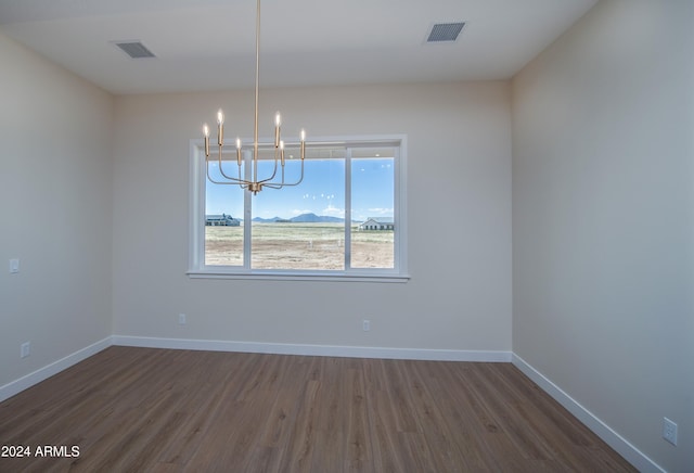 unfurnished dining area with dark hardwood / wood-style flooring, a mountain view, and an inviting chandelier