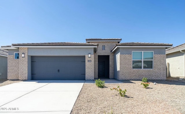 prairie-style house with a garage, concrete driveway, and brick siding