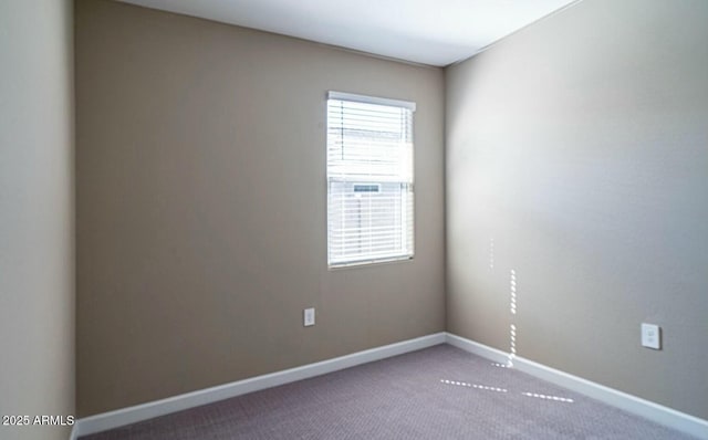 carpeted spare room featuring baseboards