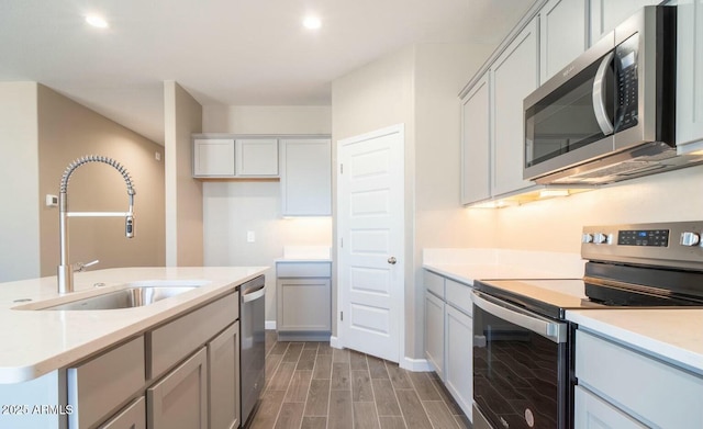 kitchen with wood finish floors, stainless steel appliances, recessed lighting, light countertops, and a sink