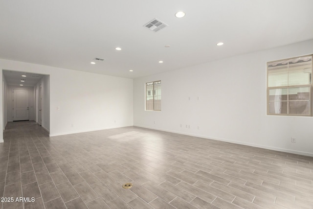 spare room with recessed lighting, wood finished floors, visible vents, and baseboards