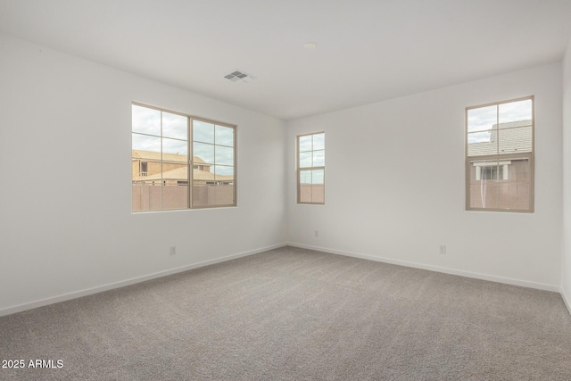 unfurnished room featuring baseboards, visible vents, and plenty of natural light