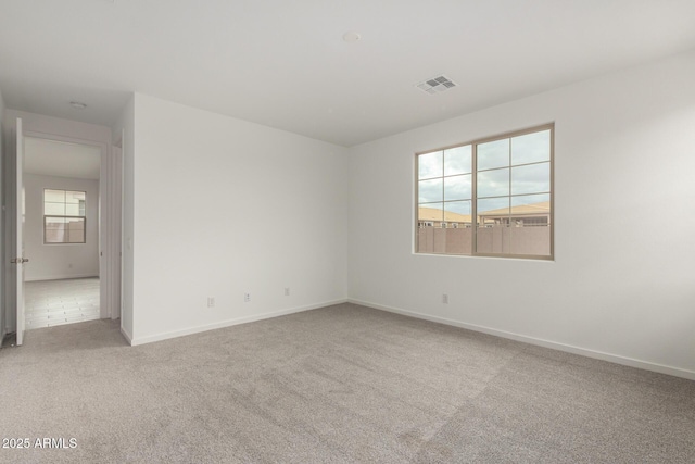 carpeted spare room featuring visible vents and baseboards