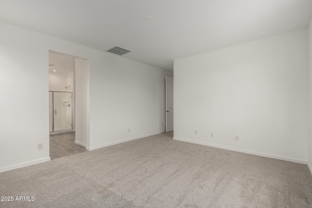 empty room featuring light carpet, baseboards, and visible vents