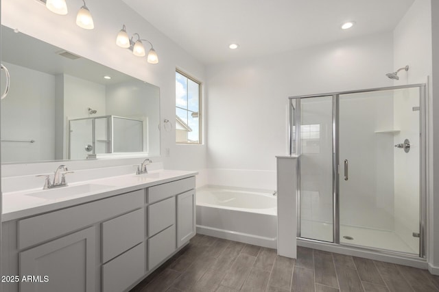 bathroom featuring double vanity, a shower stall, a garden tub, and a sink