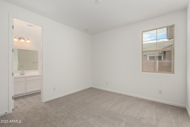 unfurnished bedroom featuring visible vents, baseboards, light carpet, and ensuite bathroom