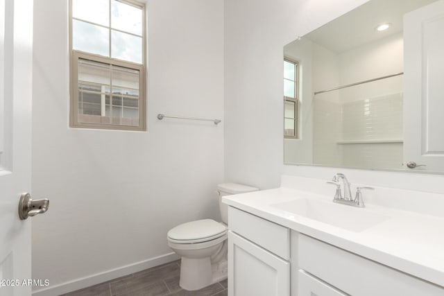 bathroom with baseboards, wood finished floors, toilet, and vanity