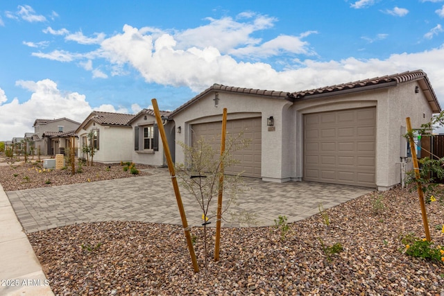 view of front of house featuring fence, stucco siding, an attached garage, a tile roof, and decorative driveway