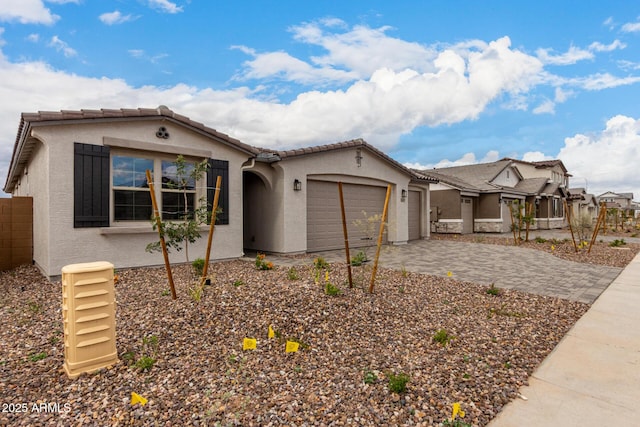 ranch-style house featuring an attached garage, a tiled roof, driveway, and stucco siding