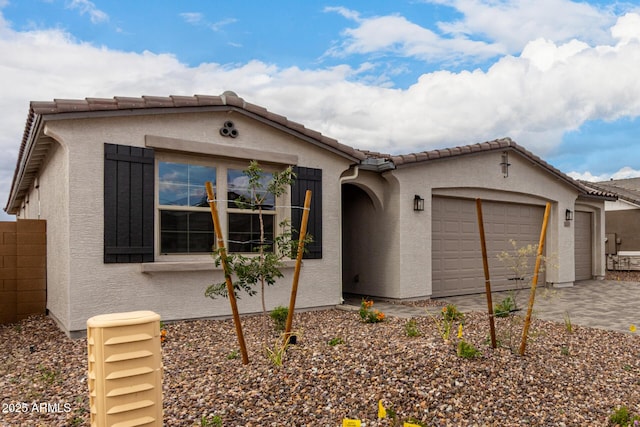 view of front of house with stucco siding, a tiled roof, driveway, and a garage