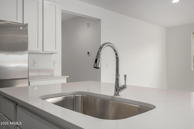 kitchen with recessed lighting, a sink, light countertops, and freestanding refrigerator