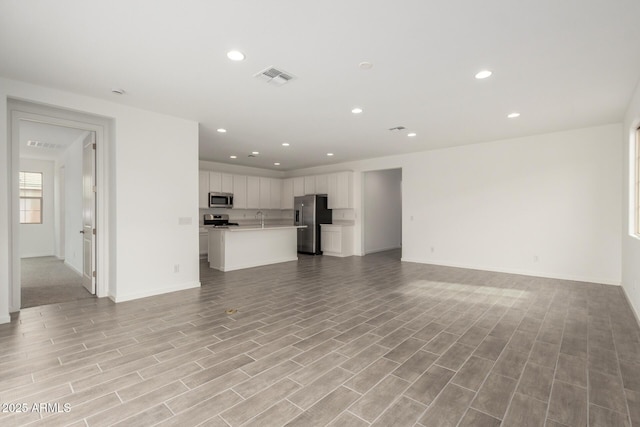 unfurnished living room with light wood-type flooring, baseboards, visible vents, and recessed lighting