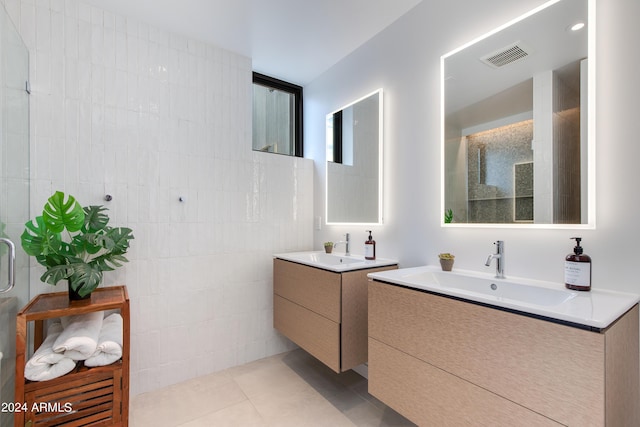 bathroom featuring a sink, two vanities, tile patterned floors, and a tile shower