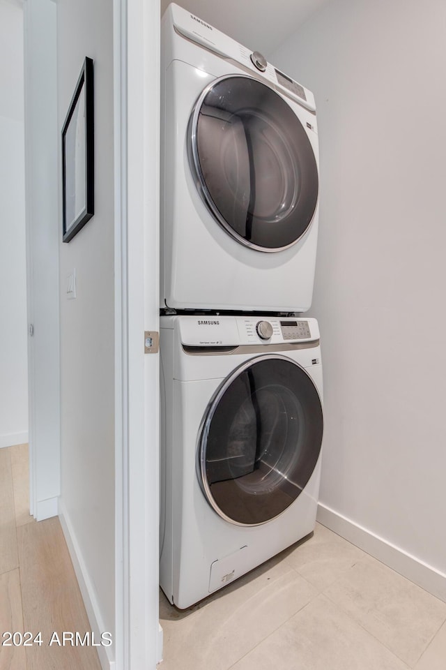 laundry room with baseboards, stacked washer and clothes dryer, and laundry area