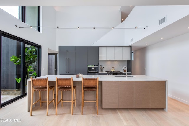 kitchen with oven, visible vents, modern cabinets, a sink, and a spacious island