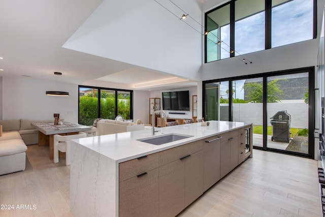 kitchen featuring light stone counters, a sink, open floor plan, modern cabinets, and light wood-type flooring