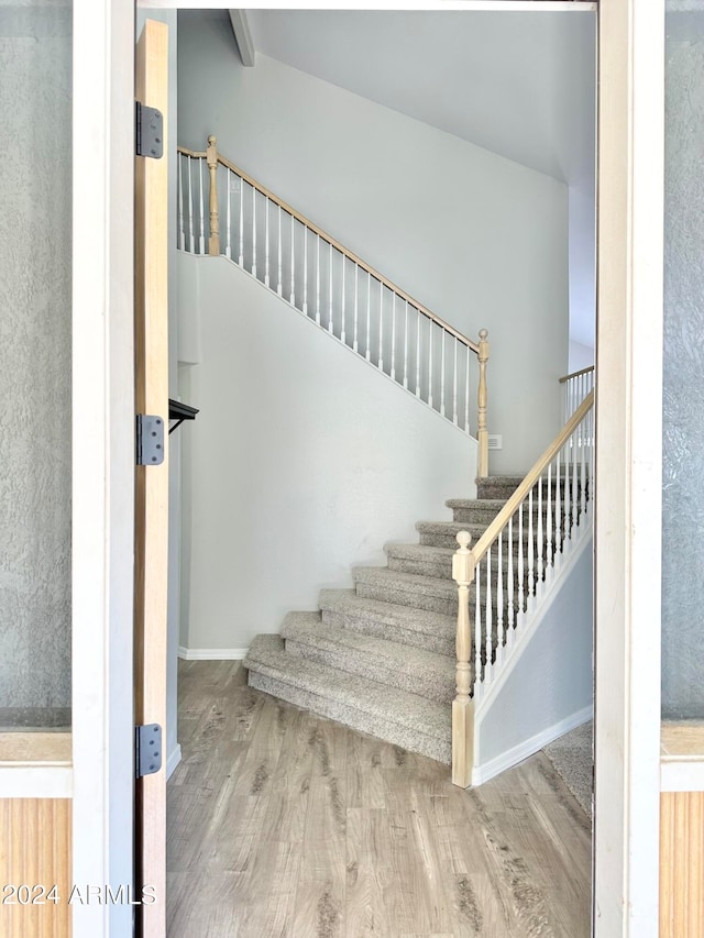 stairway featuring hardwood / wood-style floors and vaulted ceiling