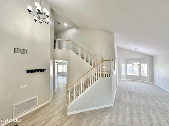 staircase with hardwood / wood-style flooring, a chandelier, and high vaulted ceiling