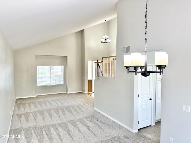 carpeted spare room featuring a notable chandelier and high vaulted ceiling