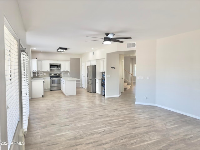 kitchen featuring tasteful backsplash, white cabinetry, ceiling fan, stainless steel appliances, and light hardwood / wood-style flooring