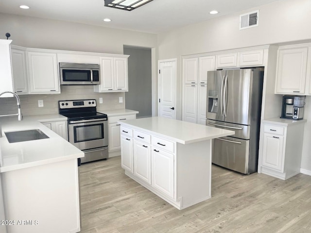 kitchen featuring sink, light wood-type flooring, a center island, stainless steel appliances, and white cabinets