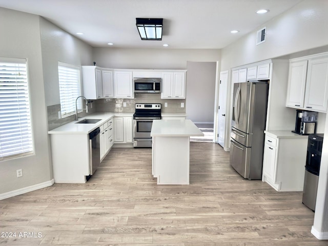 kitchen with a center island, white cabinetry, stainless steel appliances, and light wood-type flooring