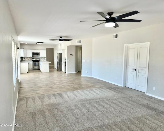 unfurnished living room with light hardwood / wood-style floors, sink, and ceiling fan