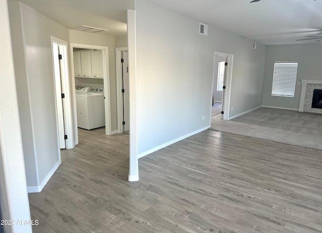 unfurnished living room featuring light hardwood / wood-style flooring, washing machine and dryer, and ceiling fan