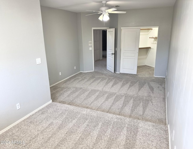 unfurnished bedroom featuring a spacious closet, ceiling fan, a closet, and light colored carpet