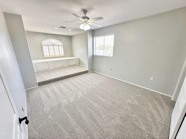 unfurnished bedroom featuring ceiling fan, multiple windows, and light colored carpet