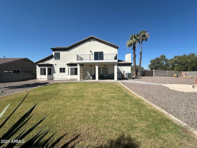 rear view of property featuring a balcony, a yard, and a patio area