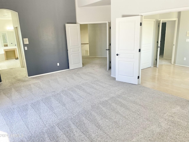 unfurnished bedroom featuring ensuite bathroom and light colored carpet