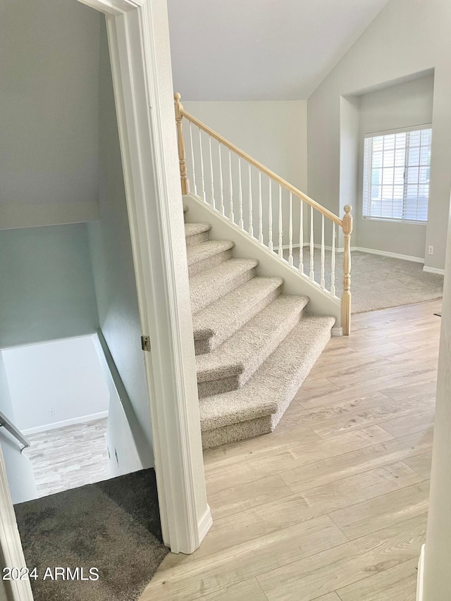 stairway with lofted ceiling and hardwood / wood-style floors