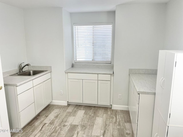 kitchen with sink, white cabinetry, and light hardwood / wood-style floors