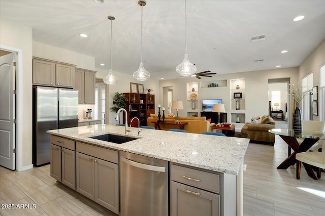 kitchen featuring pendant lighting, a kitchen island with sink, sink, ceiling fan, and appliances with stainless steel finishes