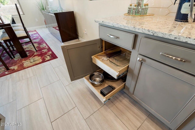 room details with gray cabinets and light stone counters