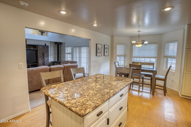 kitchen featuring a kitchen island, a wood stove, light hardwood / wood-style flooring, and white cabinetry