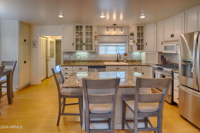 kitchen with a kitchen bar, white cabinets, appliances with stainless steel finishes, and light wood-type flooring