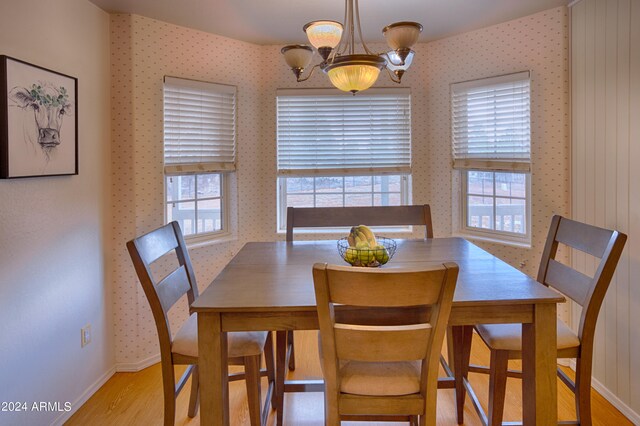 dining area with light hardwood / wood-style flooring and a notable chandelier