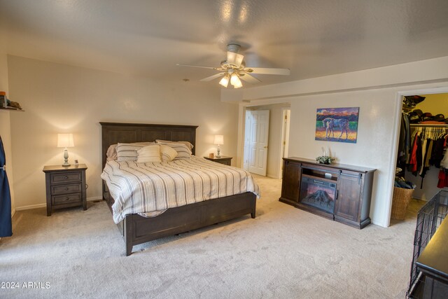 bedroom featuring ceiling fan, a closet, light carpet, and a walk in closet