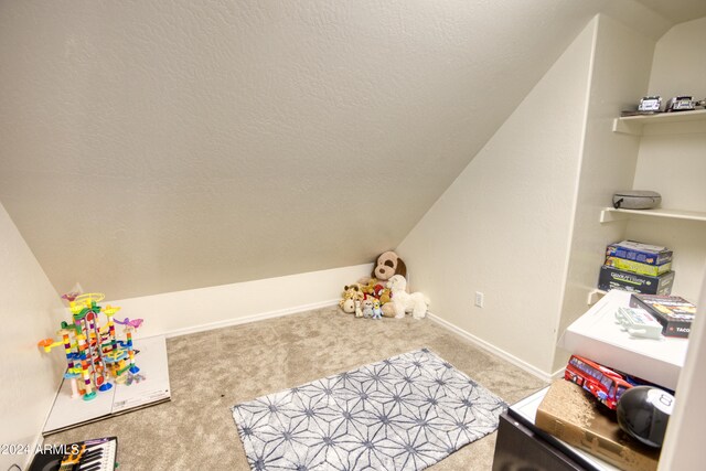 playroom featuring a textured ceiling, light colored carpet, and vaulted ceiling