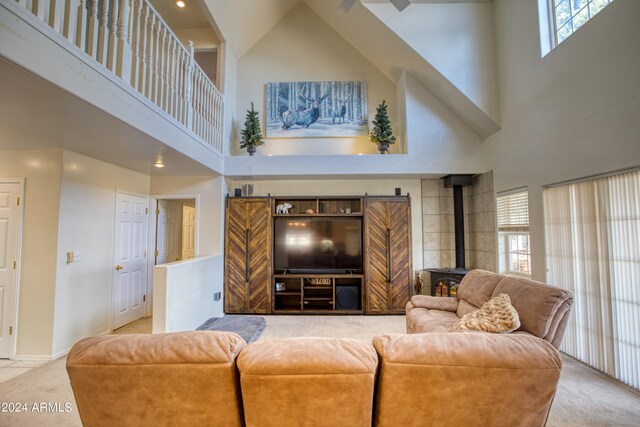 carpeted living room featuring a wood stove and a high ceiling