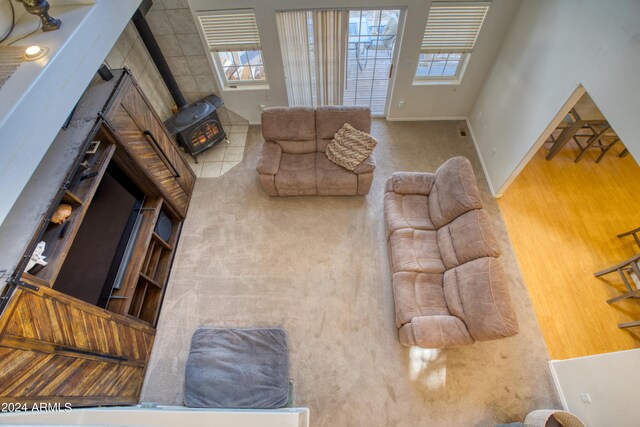 living room featuring wood-type flooring, a wood stove, and a towering ceiling