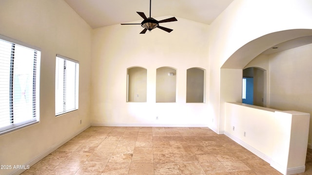 empty room with ceiling fan and high vaulted ceiling