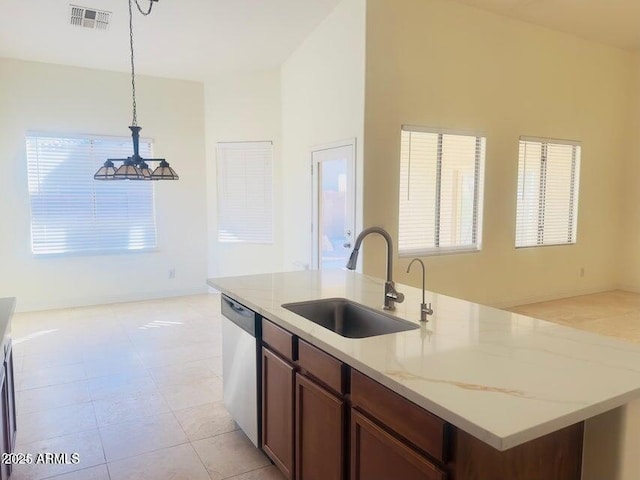 kitchen featuring sink, dishwasher, light stone counters, a center island with sink, and decorative light fixtures