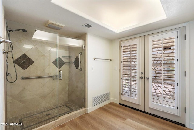 bathroom with french doors, hardwood / wood-style flooring, and a shower with shower door