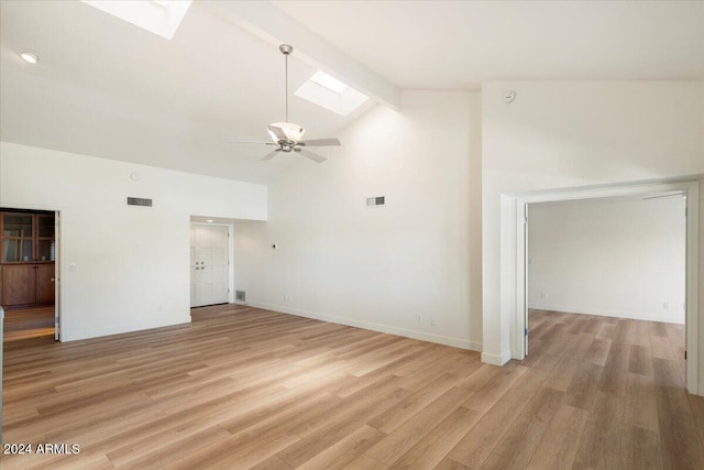 unfurnished living room featuring high vaulted ceiling, a skylight, ceiling fan, light wood-type flooring, and beam ceiling